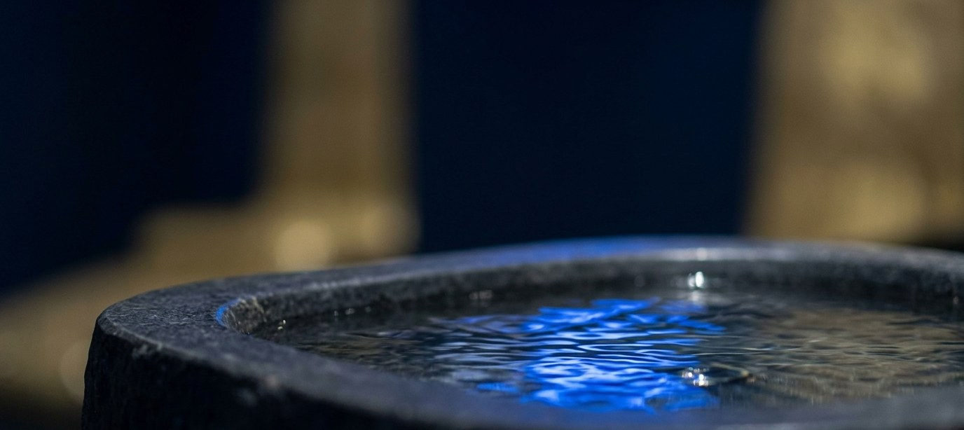 Softly lit stone water feature glowing blue at Float Therapy Wilmslow