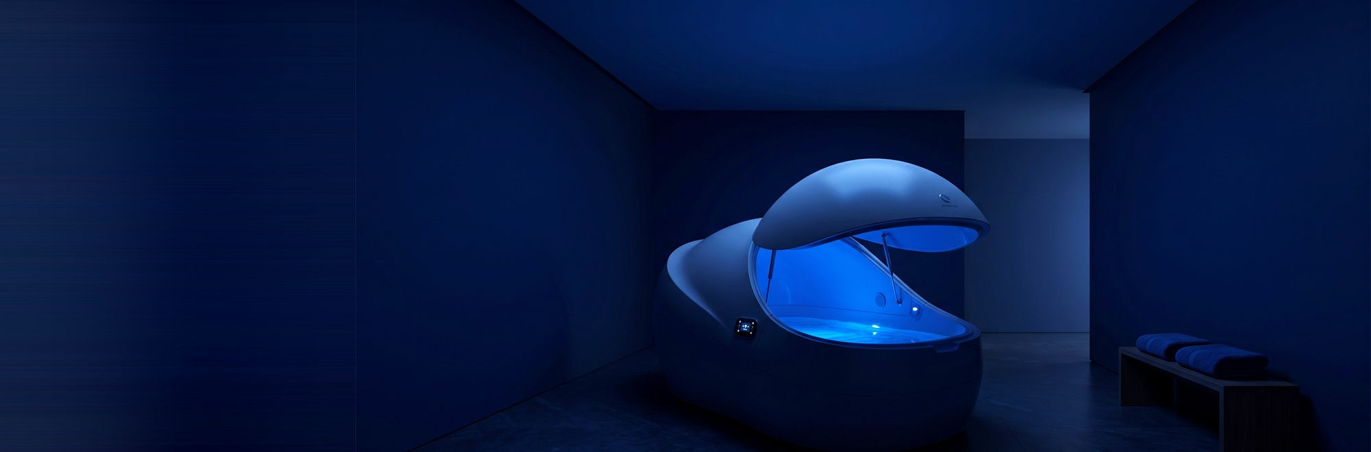 Float therapy pod glowing softly blue in a calm, darkened suite at Float Therapy Wilmslow